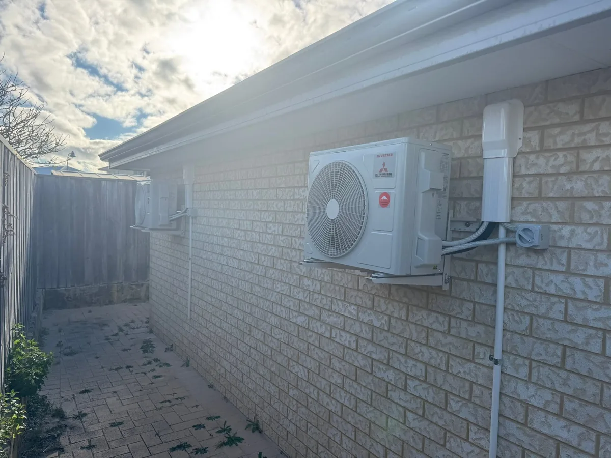 Split system air conditioning condenser mounted on a brick wall with a neatly run conduit