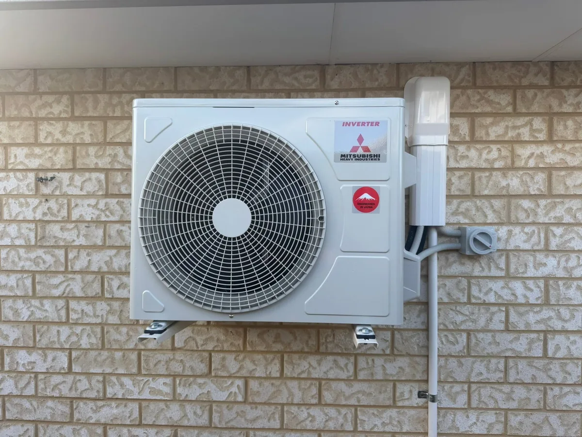 Mitsubishi Electric split system outdoor unit installed on a limestone block wall