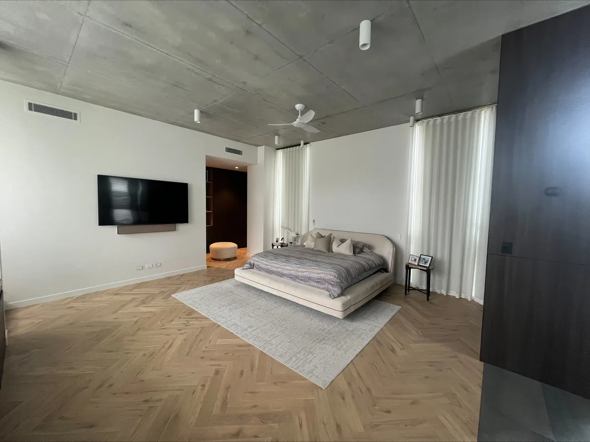 Master bedroom with a ceiling fan, recessed lighting and a wall-mounted TV point over herringbone timber flooring