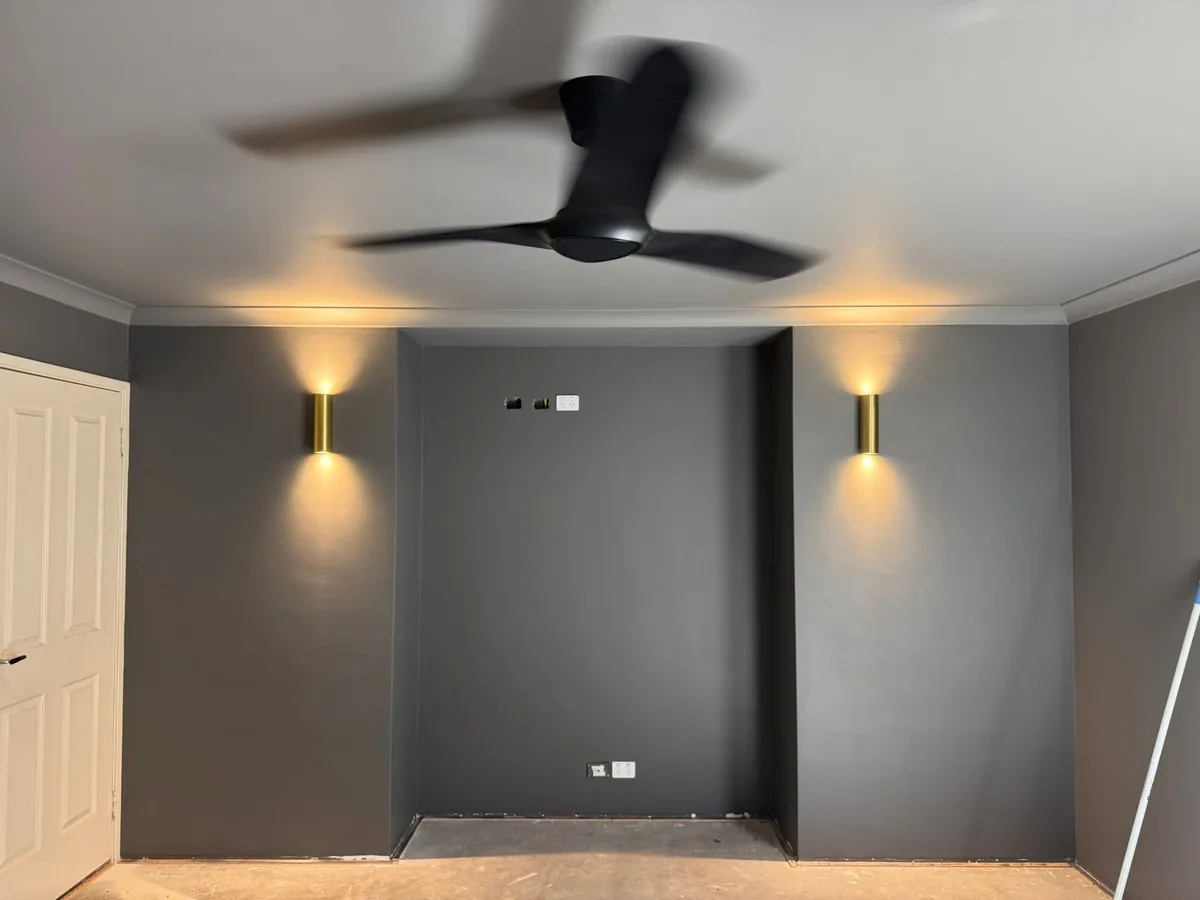 Bedroom with brass up-and-down feature wall lights and a black ceiling fan installed