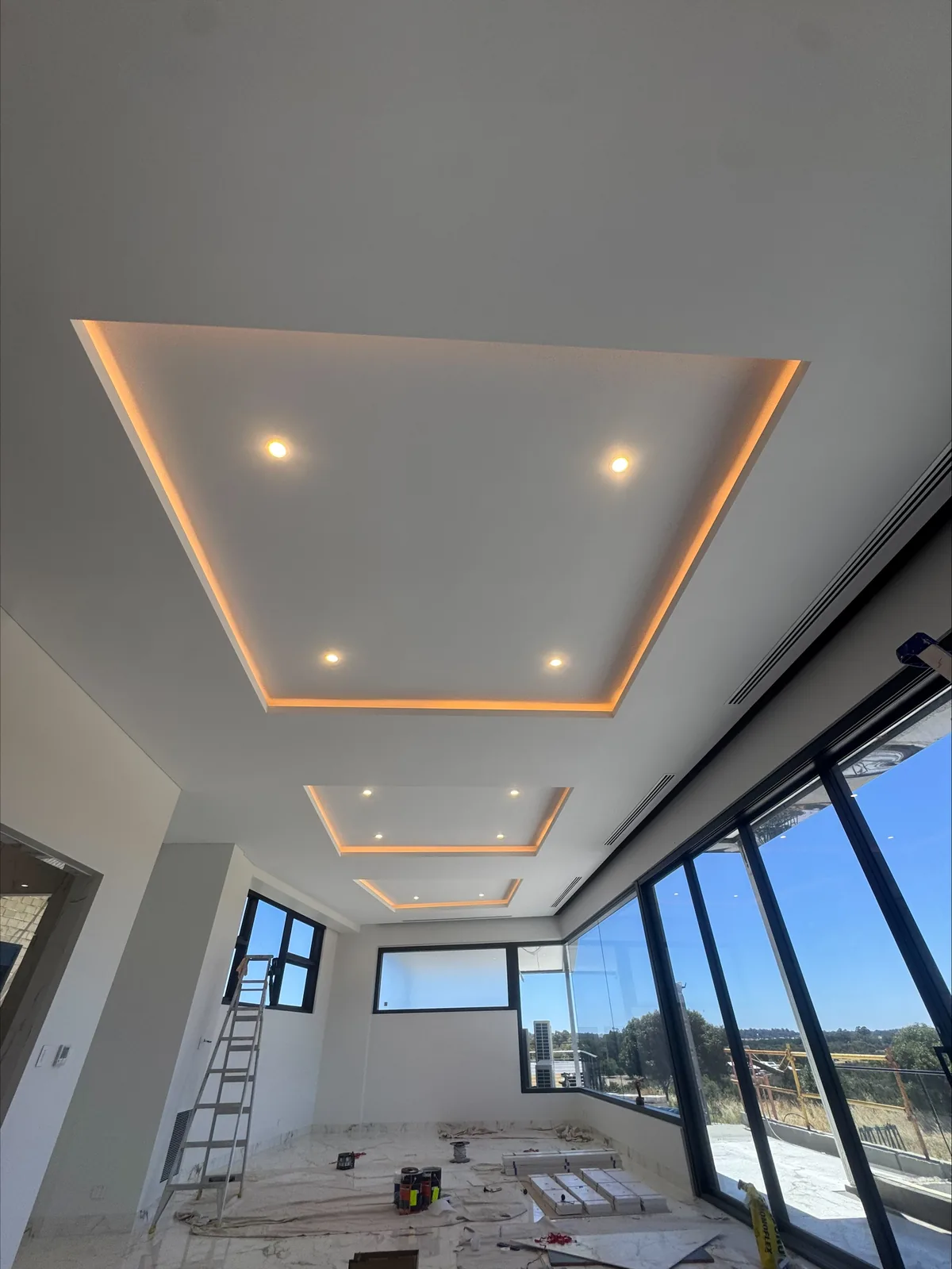 Coffered ceiling detail lit with a warm concealed LED strip above floor-to-ceiling glazing
