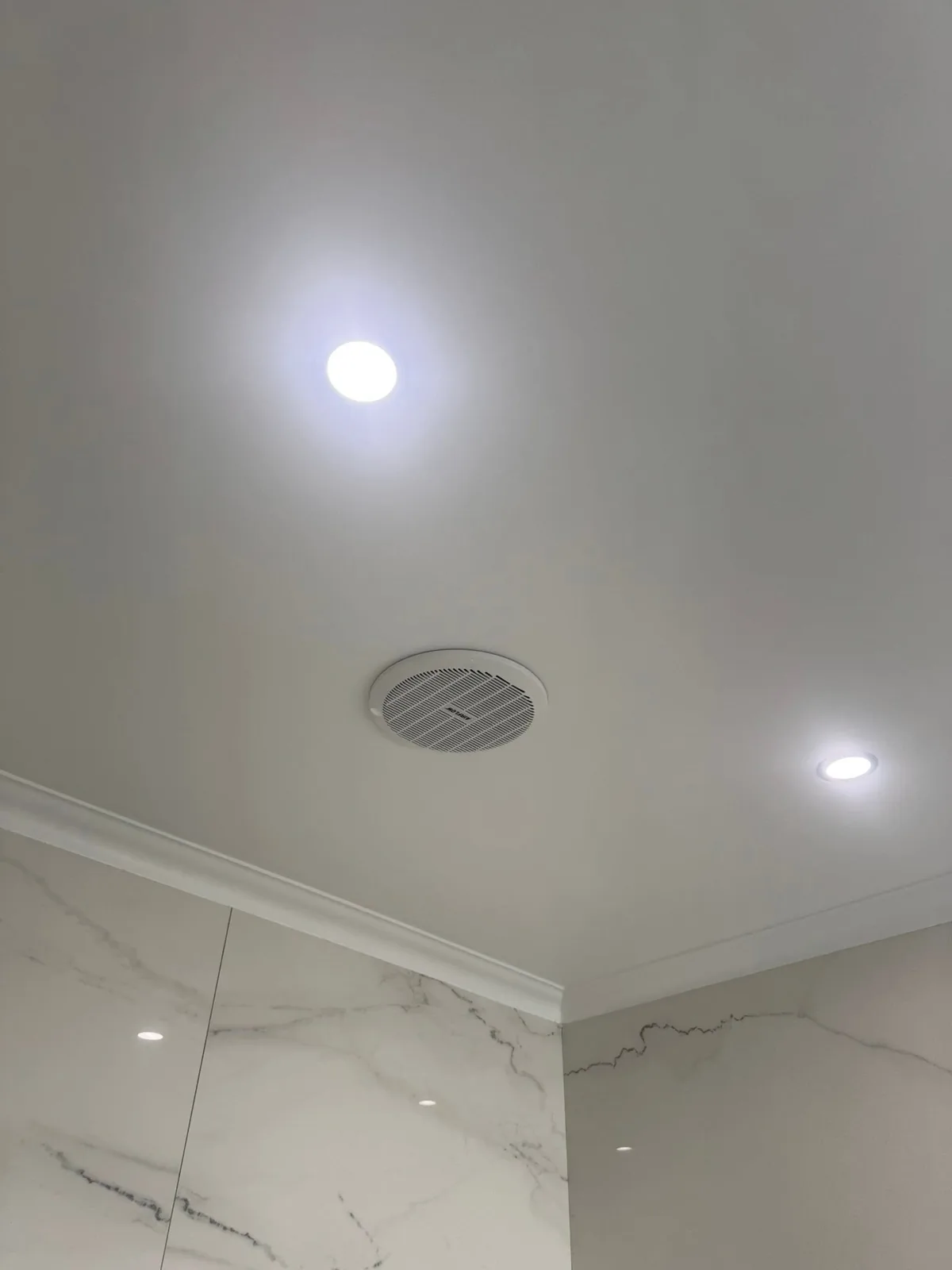 Ceiling exhaust fan and LED downlights installed in a marble-tiled ensuite