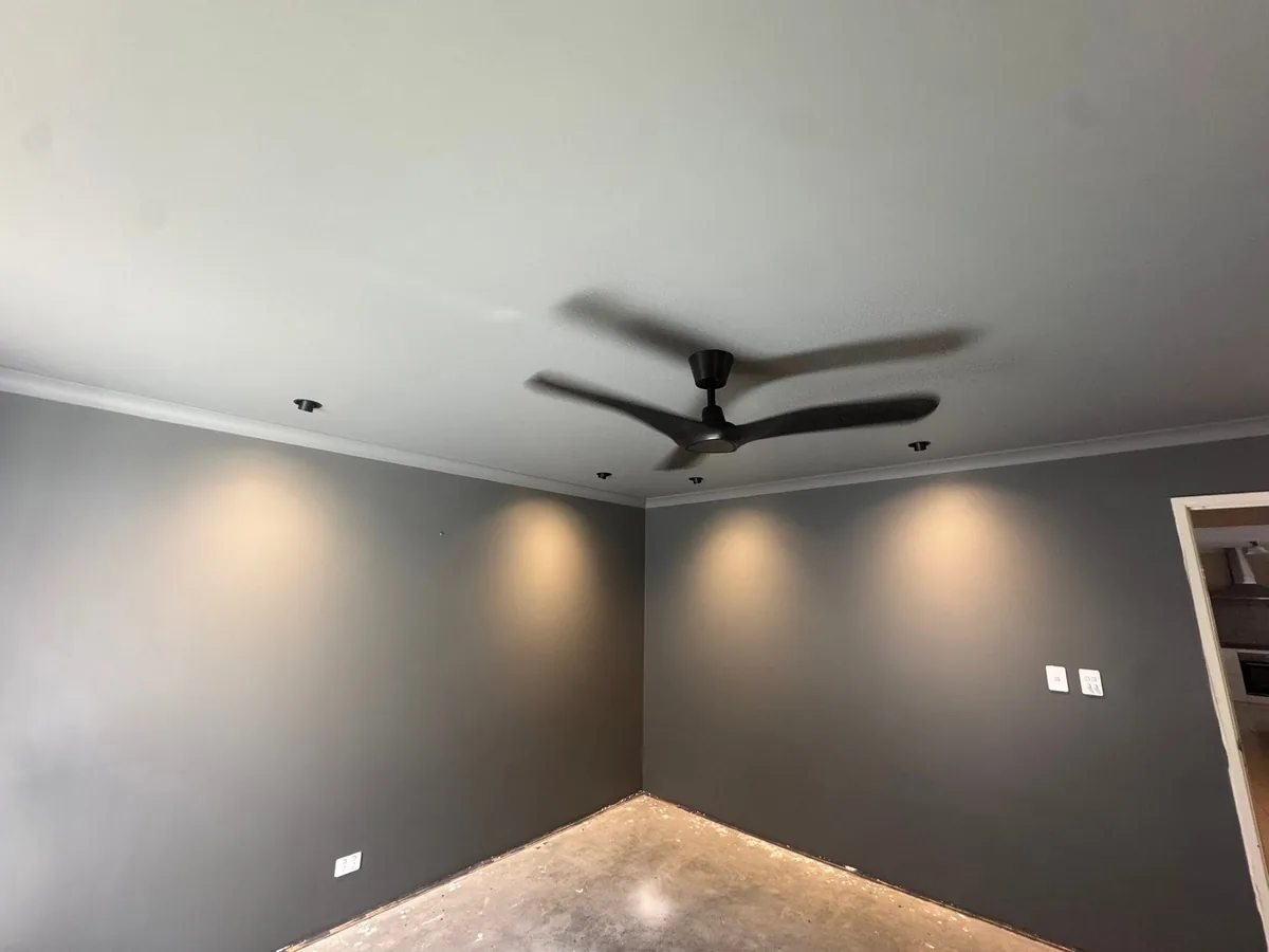 Living room with new LED downlights and a ceiling fan installed before handover