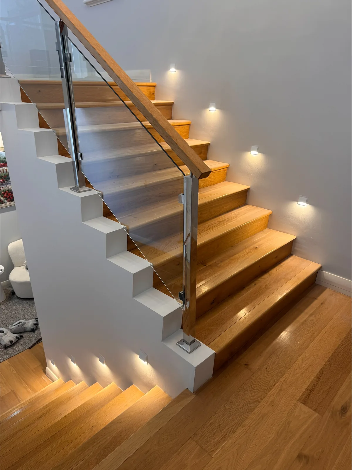 Timber and glass staircase with warm LED step lighting installed into each tread