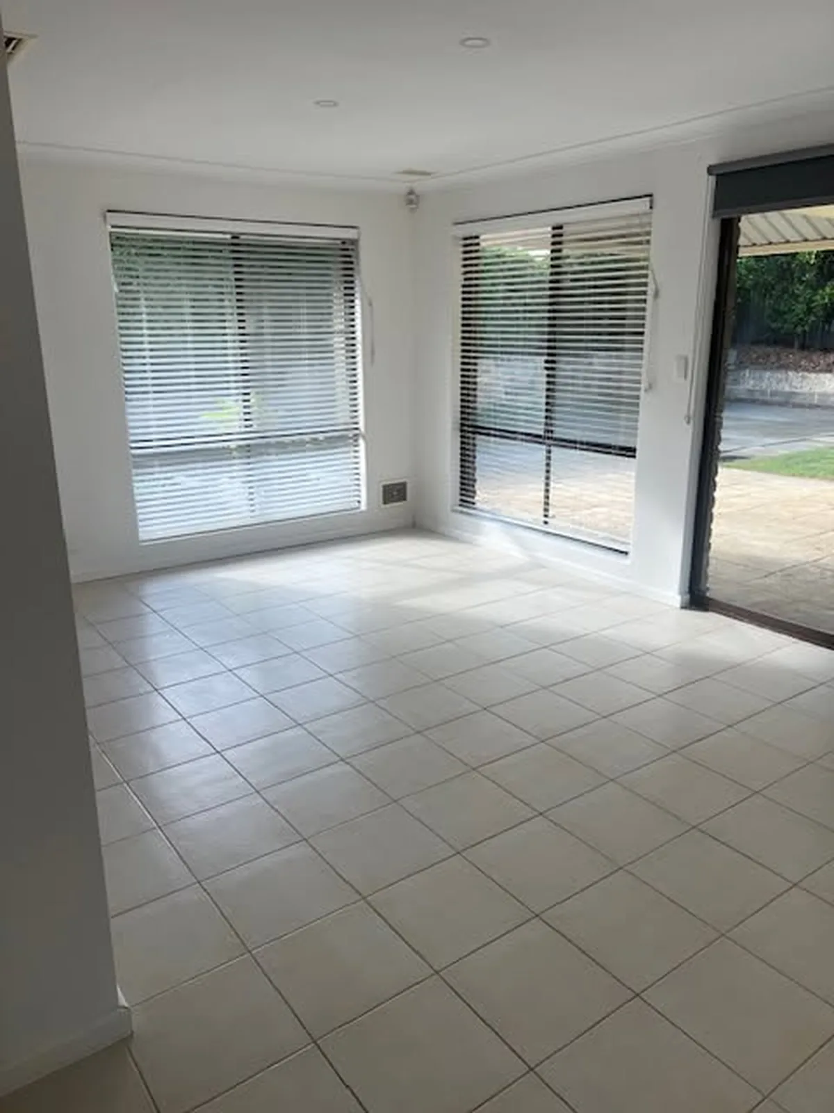 Empty living area with clean tiled floors and windows ready for handover to the agent