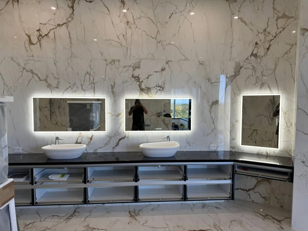 Commercial washroom with marble-look wall panels, twin basins and backlit LED mirrors